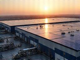 Sprawling manufacturing plant with solar panels covering a significant portion of its roof, symbolizing massive energy cost reduction.